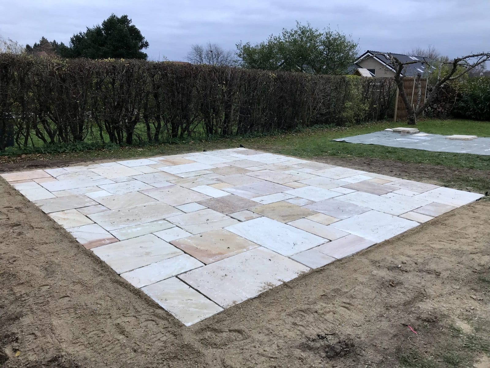 Nyudlagt terrasse med lyse stenfliser i haven