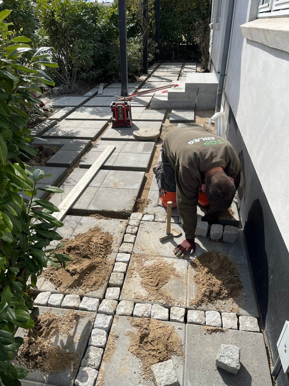 Håndværker lægger fliser i husets havegang