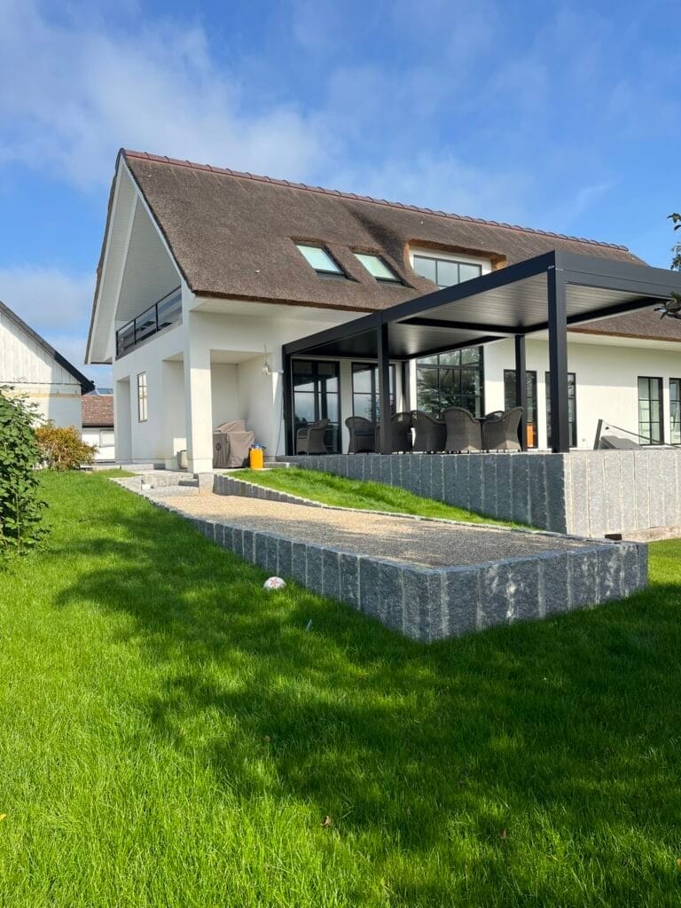 Moderne hvidt hus med stråtag og terrasse