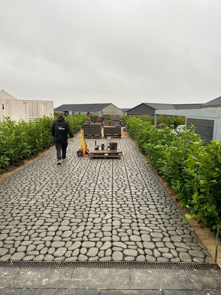 Anlægsarbejder lægger belægningssten i indkørsel.